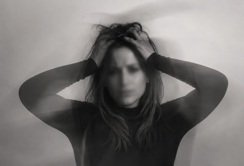 Mulher em sofrimento emocional com expressão de ansiedade e tensão mental em imagem artística desfocada